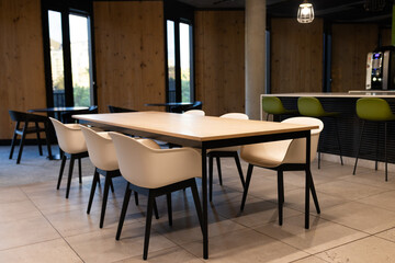 Modern office break room with empty chairs and table, ready for meetings, copy space