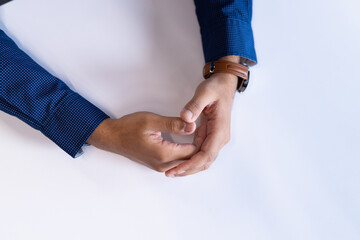 Close-up of hands resting on table, wearing blue shirt and brown watch, copy space