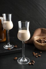 Coffee cream liqueur in glasses and beans on black wooden table