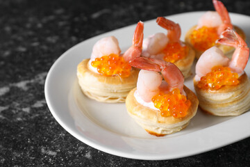 Delicious puff pastry with shrimps, cream cheese and red caviar on dark table, closeup