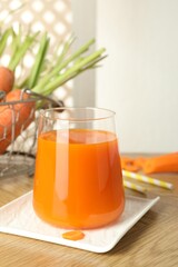 Healthy juice in glass and fresh carrot on wooden table