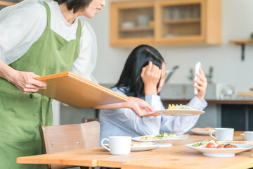 Fototapeta premium 食事中にスマホを使う反抗期の子供と困る両親・家族 