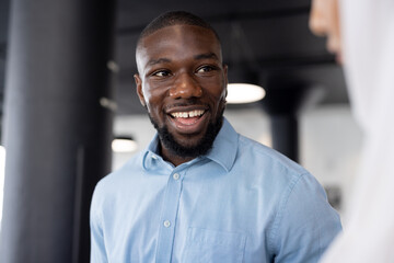 Smiling businessman in blue shirt engaging in conversation at office