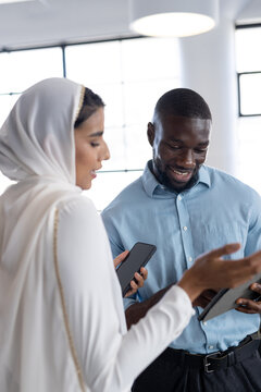 Discussing work, business colleagues using smartphones and tablet in office setting