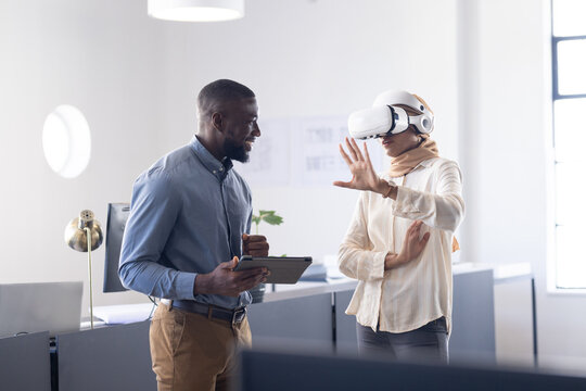 Using VR headset, woman interacting with virtual environment, colleague observing