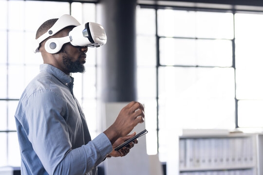 Using VR headset, man interacting with virtual environment while holding tablet