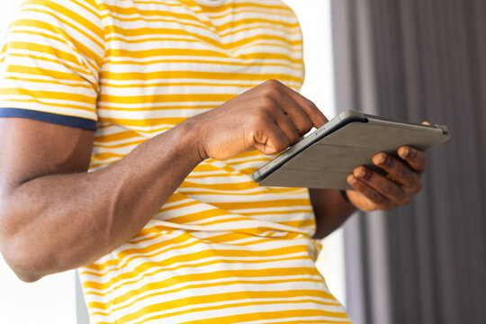 Using tablet, man in striped shirt browsing or working at home