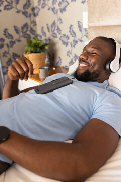 Relaxing at home, African American man listening to music with headphones