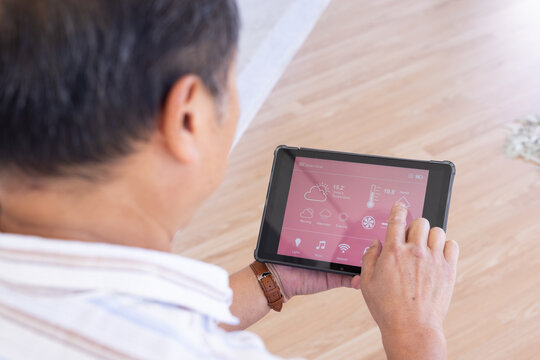 Using tablet, senior senior man controlling smart home system with weather app