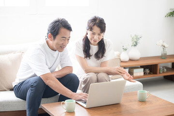 Fototapeta premium A couple in their 50s discussing over a computer in a bright, clean living room Image looking for real estate or travel