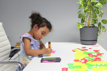 4 year old Latina girl with brunette curly hair draws as therapy with the school psychologist for Attention Deficit Disorder TDAH in Spanish