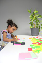 4 year old Latina girl with brunette curly hair draws as therapy with the school psychologist for...