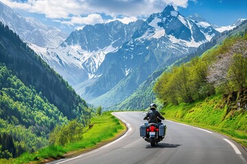 motorcyclist riding along the winding mountain road, surrounded by lush greenery and majestic mountains in springtime.