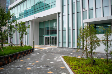 Glass entrance of a downtown office building and landscaping with trees and lawn
