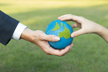 Businessman hand giving Earth globe to little boy as Earth day concept as corporate social...