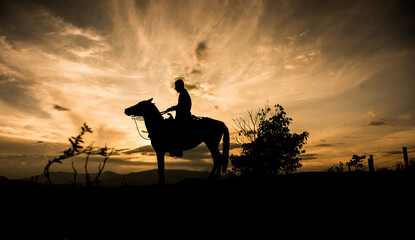 silueta de hombre en caballo al atardecer 