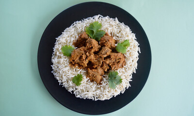 A top view og lamb korma with basmati rice and coriander leaves.