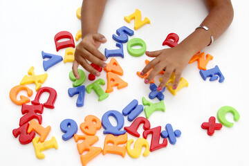 Brown hands of mom and daughter play with the game of colored letters as language therapy for...