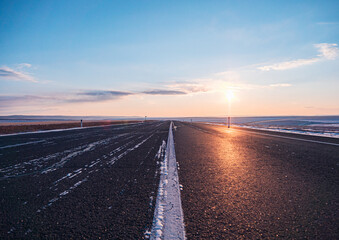 Empty rural road at sunset in winter with clearing skies