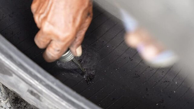 Car mechanic repairs punctured tire hit by nail on rim in service workshop. Close-up of a mechanic at a tire service shop changing a tire.