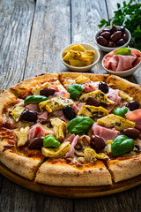 Circle pizza capricciosa slices prepared with cooked ham, mozzarella, artichoke, sliced mushrooms...