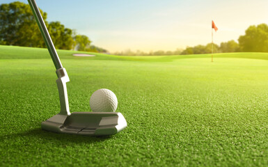 Close-up golf ball and golf putter before putting to the hole.