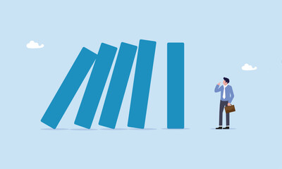 Obraz premium Courage businessman thinking look at collapsing domino effect, risk management, uncertainty or unknown threat causing business failure, economic crisis, danger or problem, security and safety concept.