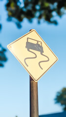 Low angle view of a slippery road warning sign post near the park.