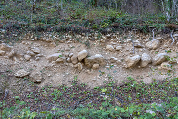 A shallow riverbed with an exposed rocky bottom, a small stream and a flow of water, autumn in nature