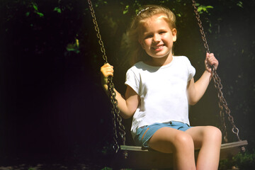 Happy child girl on swing, summer time. Life Events. Retro toned, Soft focus effect