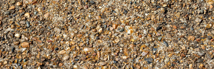 Large and small pebbles on the surface of concrete, top view. Various-sized pebbles, flat layout. Pebbles of different sizes lie chaotically.