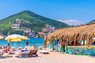 People relax and unwind on the seashore in Montenegro with a picturesque view of the mountains,...