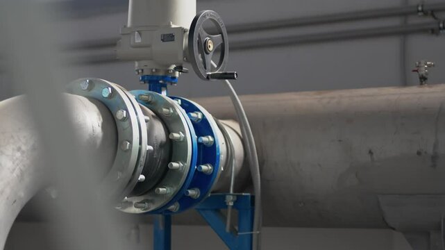 Metal pipe with flange connected to pipeline at chemical plant. Water distribution pipeline installed at refinery factory featuring heavy equipment