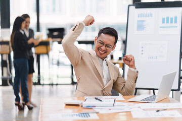 A businessman celebrates successful business deal at desk in meeting room.