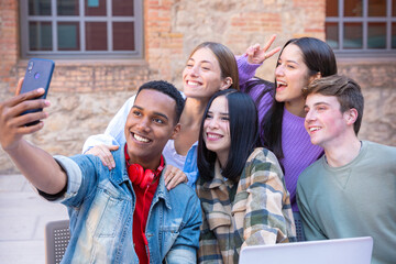Five young multiracial friends taking a selfie portrait together outdoors
