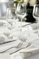 Empty glasses and silverware resting on a table set with white linen
