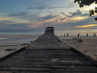 Enjoying the beach atmosphere at sunset on the wooden pier bridge of Maratua Island., East Kalimantan
