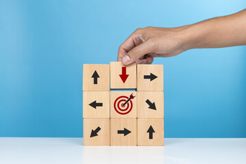 Concept of purposeful movement towards the goal. Hand hold wooden cube with red arrow moves towards...