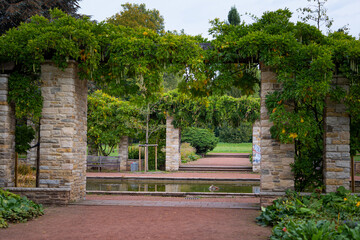 A beautiful park landscape with a stone brick pavilion and blooming plants. Autumn scenery of Nordpark, Dusseldorf, Germany.