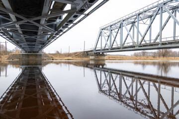 A beautiful springtime scene under the old metal railway bridge over the river. Metal construction from below.