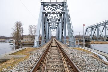 Obraz premium Close-up of the railway tracks over the metal truss bridge. Springtime scenery in Riga, Latvia.
