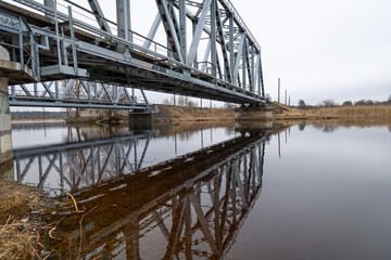 Two parallel metal truss bridges with railway tracks over the river. Springtime outdoors scenery of Riga, Latvia.