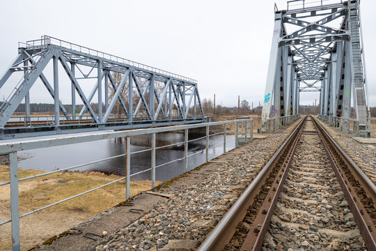 Two parallel metal truss bridges with railway tracks over the river. Springtime outdoors scenery of Riga, Latvia.