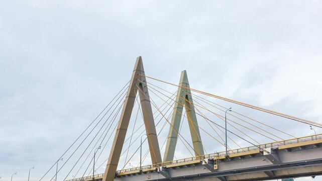 Millennium bridge with letter shaper arch over river in Kazan time-lapse. Modern transport overpass under gloomy sky. Urban infrastructure