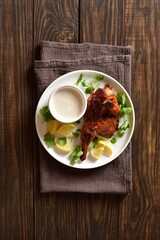 Roasted half chicken on white plate over wooden background