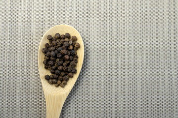 Pile of Black peppercorns Black pepper dried seeds on glass plate wooden background
