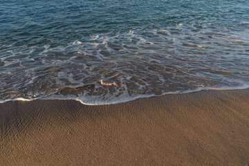 Waves rolling on a sandy beach on a sunny day