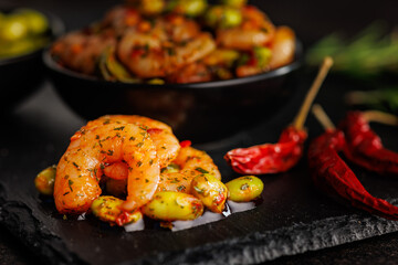Fresh salad with shrimps and edamame soybeans on black cutting board.