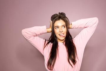 Naklejka premium Shot of funny young long haired brunette woman showing tongue to camera, isolated over pink background