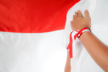 man's hand on chest, with indonesian flag background, independence day